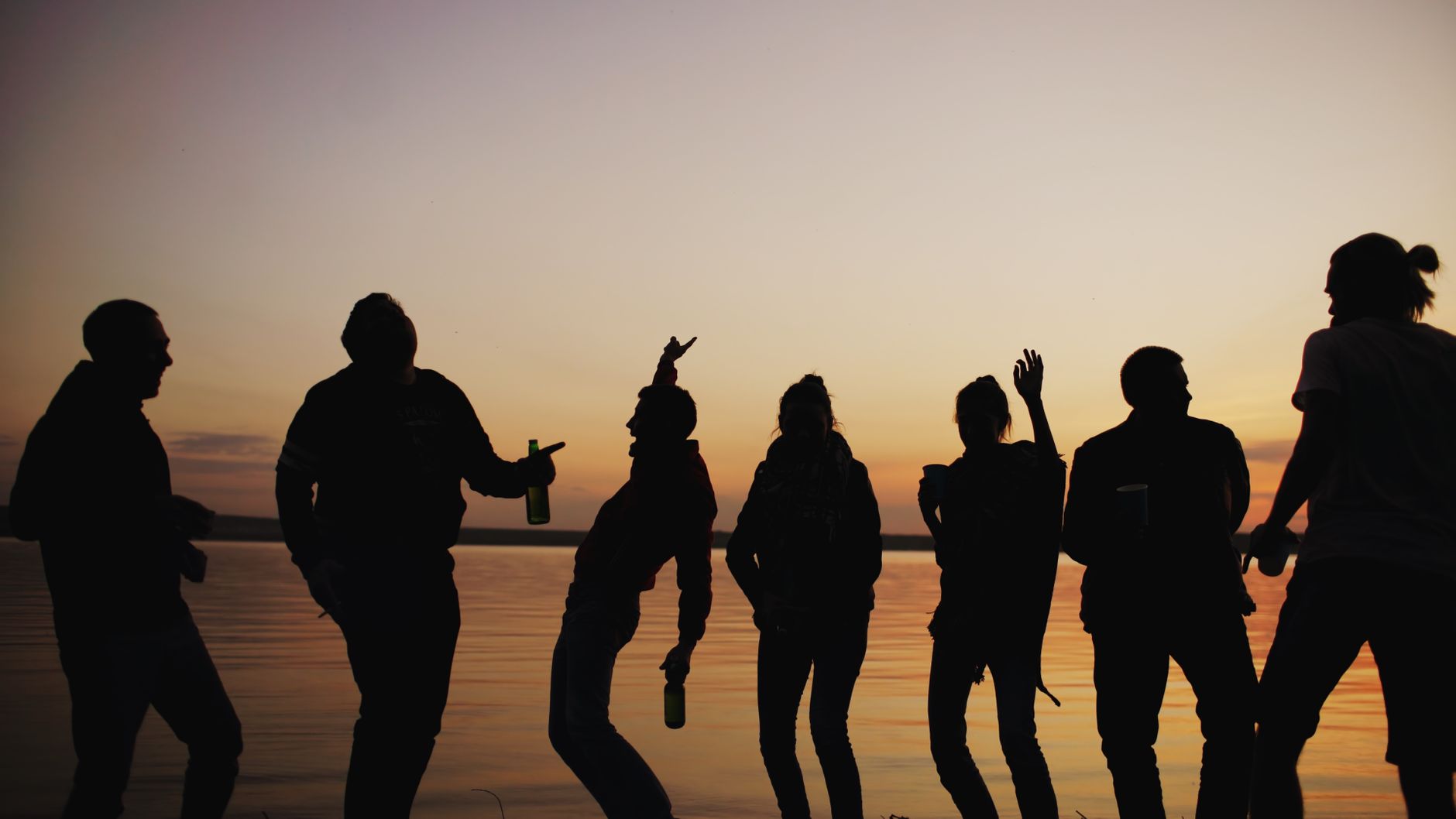 silhouette friends enjoying sunset by lake